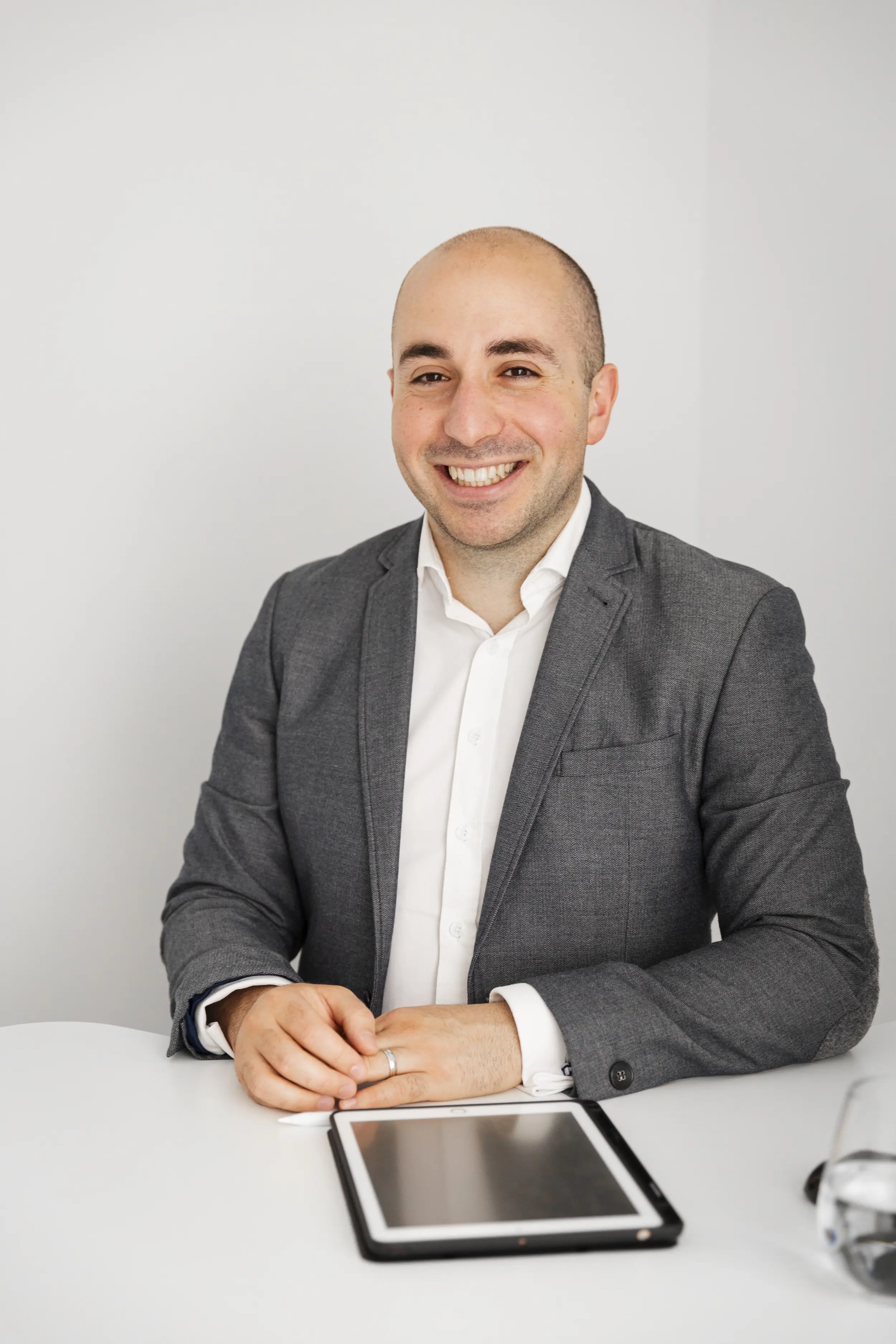 Robert Daniele in a suit smiling at the camera with an ipad in front of him.