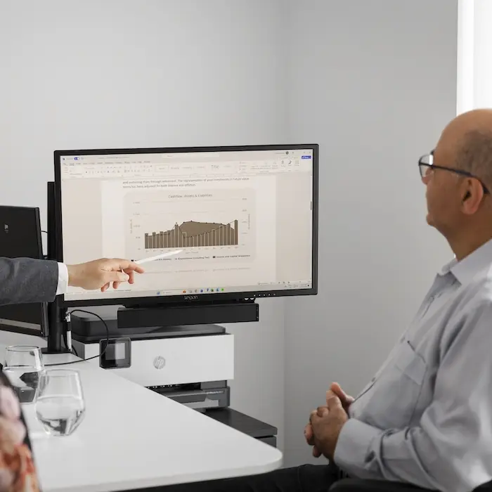 Robert Daniele pointing at a computer screen explaining finance.