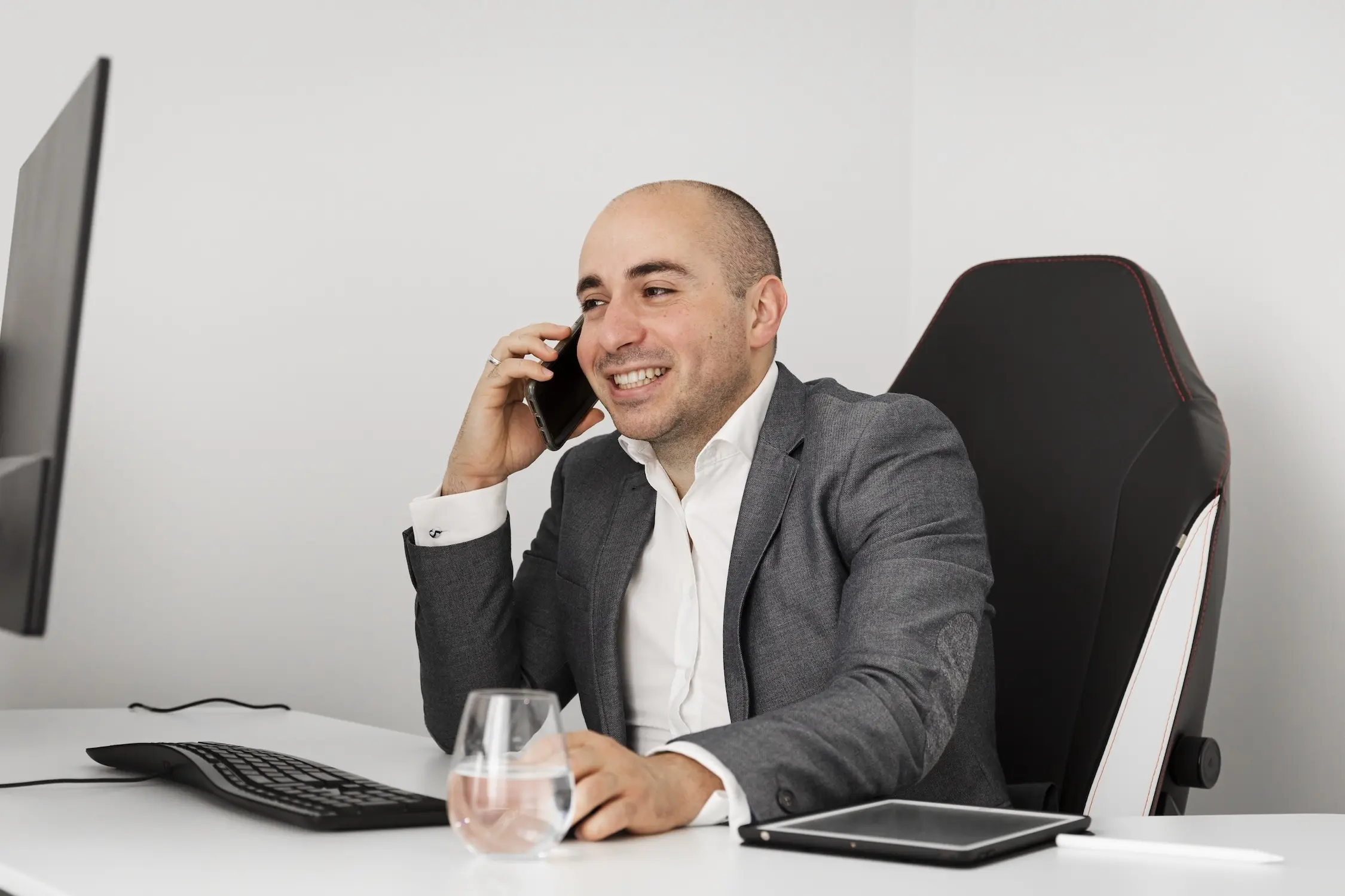 Robert Daniele talking on the phone with a client at his computer with a glass of water.